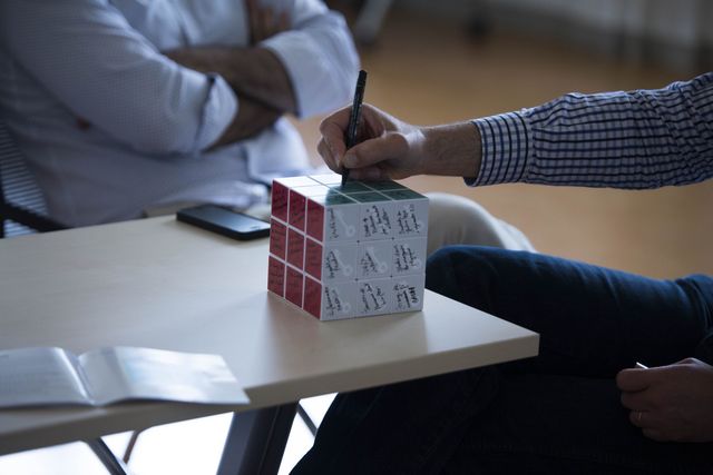 A participant writing in marker on the white face of a cube