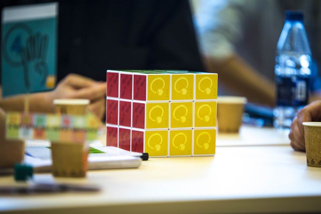 A completed cube with red and yellow faces on a workshop table